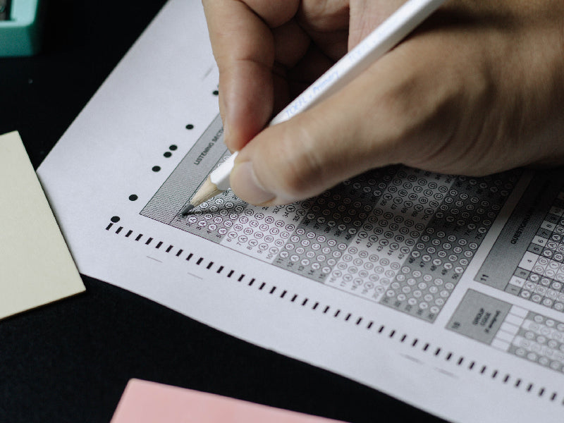Main remplissant une grille de test avec un crayon, illustrant le test pour évaluer l’anxiété et l’éreutophobie